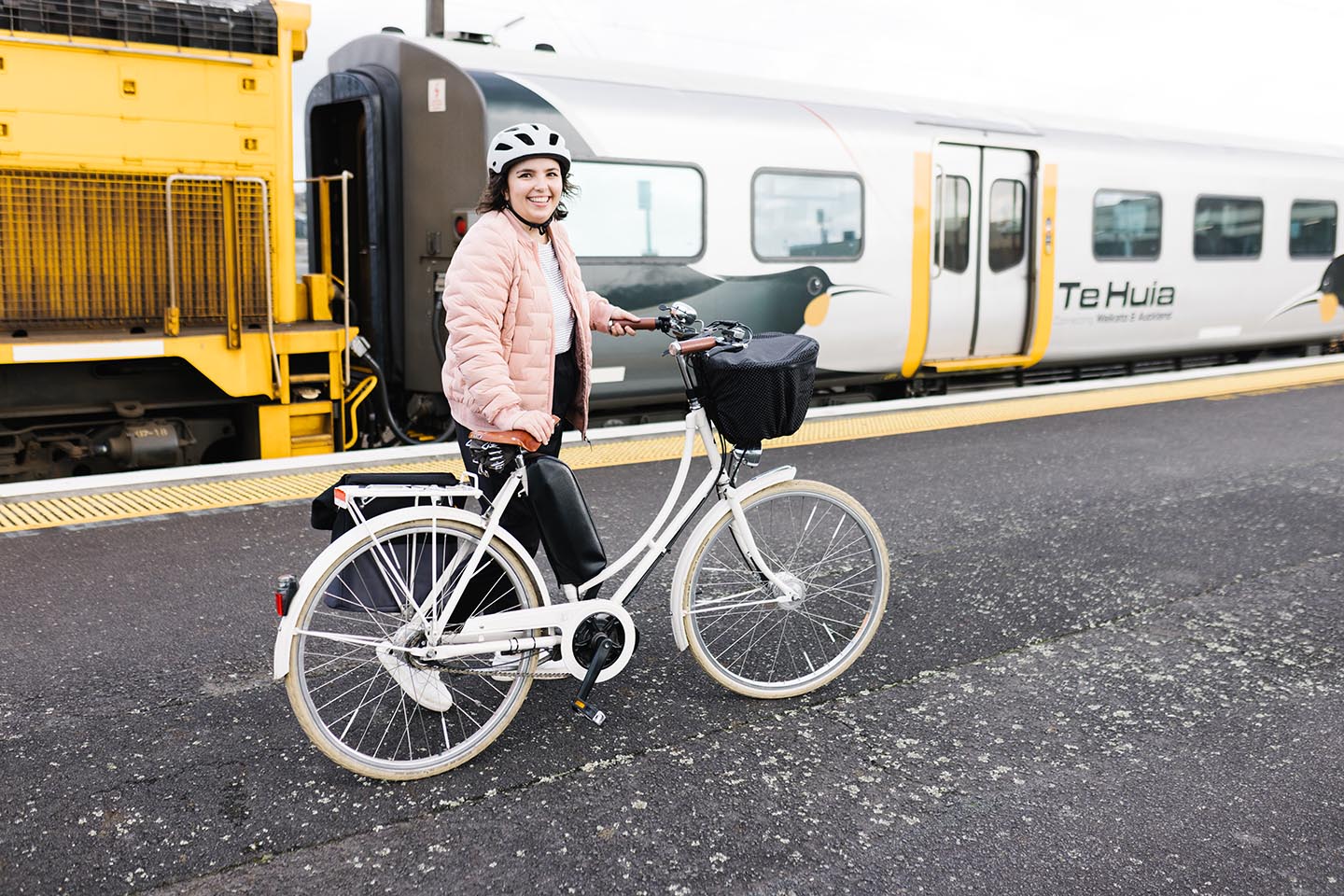 Louise walking her bike alongside Te Huia, the Hamilton-to-Auckland passenger train